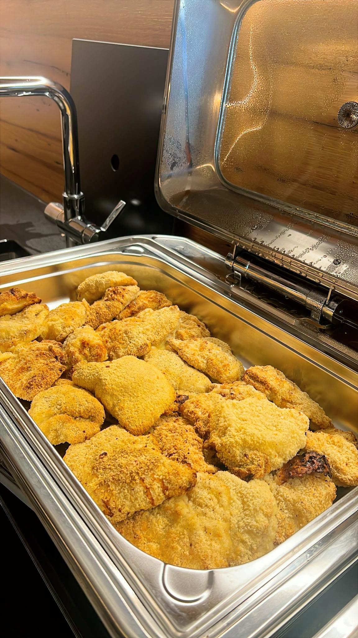 Knusprig gebackene Schnitzel liegen goldgelb in einer geöffneten Edelstahlschale