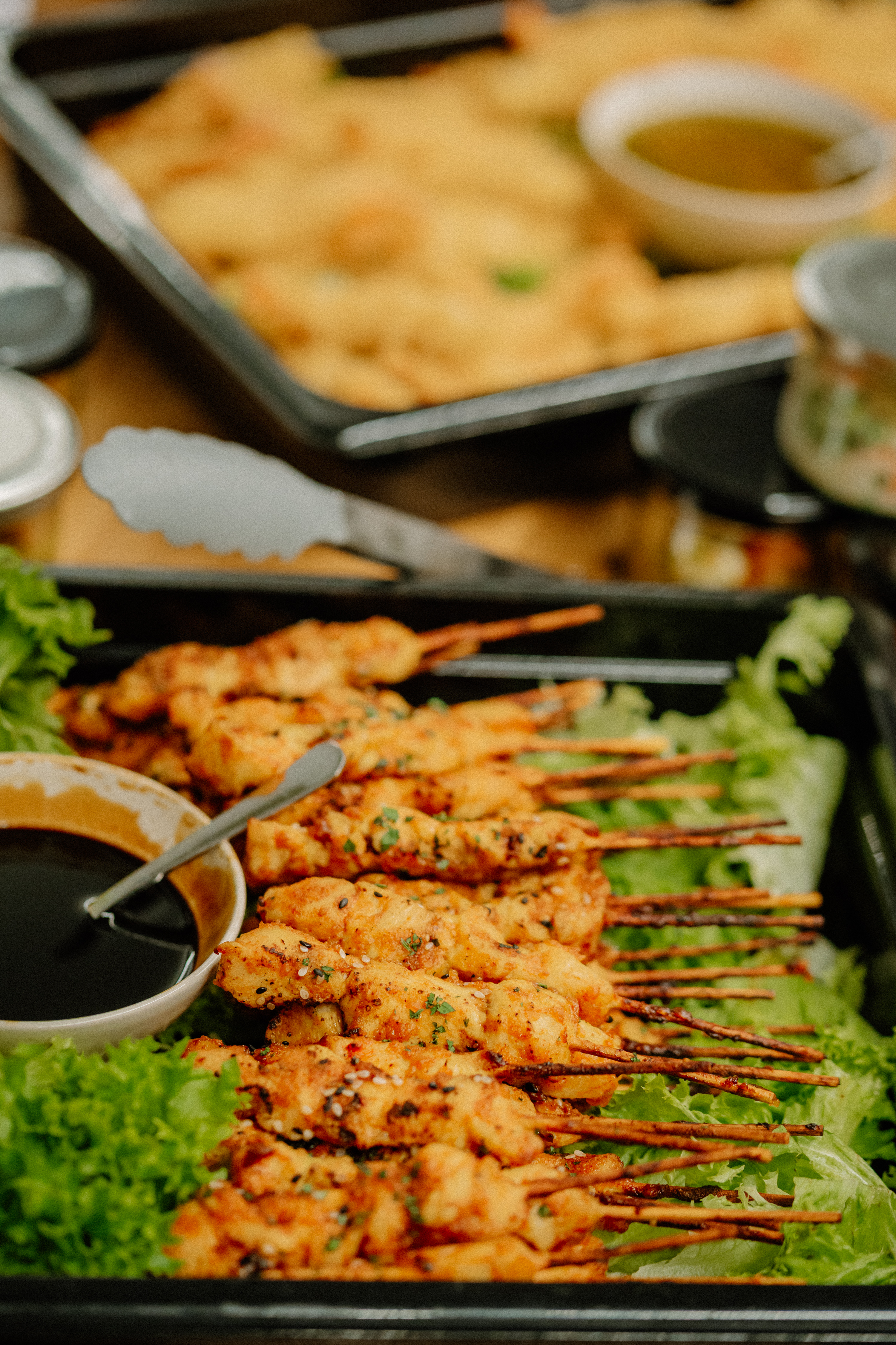 Gegrillte Haehnchenspiesse auf Salat mit dunkler Dipsauce auf Buffet